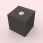 NUDE gift wrapping example, black wrapping paper with the icons of glassware in pink. Finished with a pink NUDE sticker